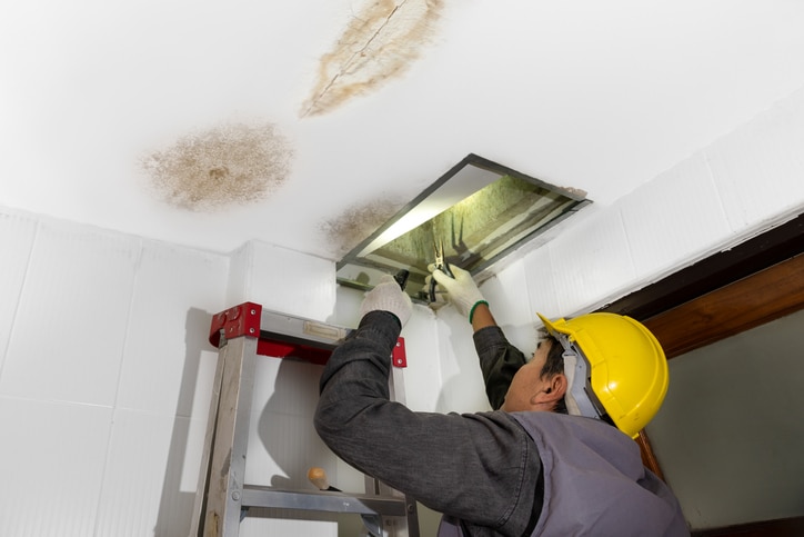Worker fix leaking pipe in ceiling ,close up of a stain on the ceiling.